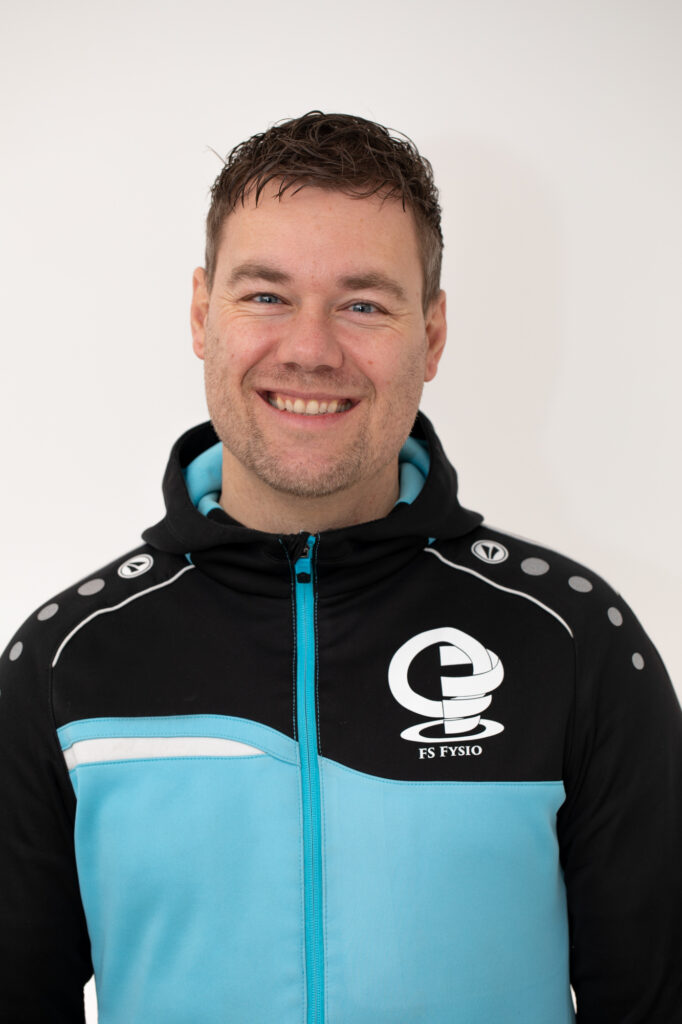 Portret van een Guido Iken in sportieve werkkleding in de praktijkruimte.
