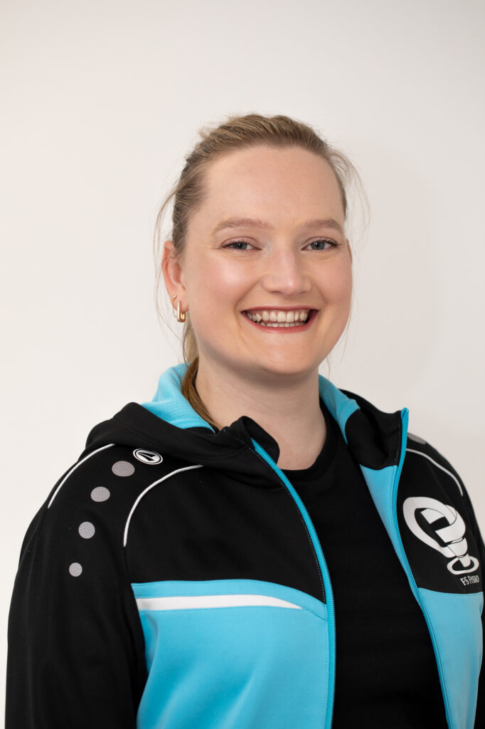 Glimlachend portret van een fysiotherapeut in praktijkkleding.